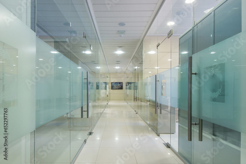 Modern office space divided by glass partitions into work areas.