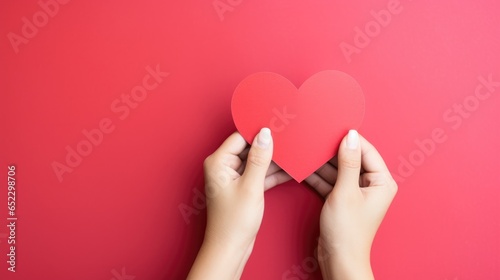Hands holding blank paper greeting or invitation card over red background with heart shape. Christmas, Valentine day, New Year, winter holidays concept.