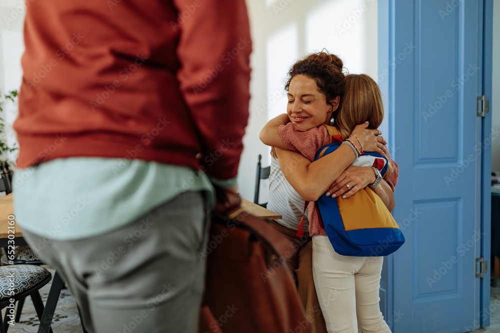 Fototapeta premium Mother hugging daughter while her father waits