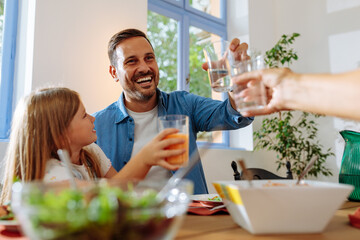 Girl and her father are doing cheers during family lunch