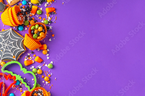 Bright colorful Halloween gingerbread cookies and sweet background. Homemade biscuits with cookie cutters, sugar sprinkles and candies. High-colored Halloween treats flat lay top view copy space © ricka_kinamoto