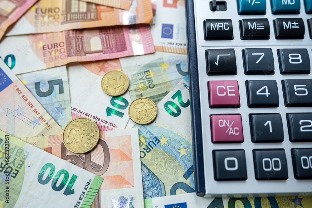Euro coin and calculator above euro bills. Saving and finance concept Euro coin and calculator above euro bills. Saving and finance concept