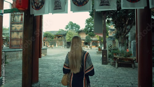 Follow Shot of a Blonde Hair Girl in a Colourful Poncho Walking on the Streets
