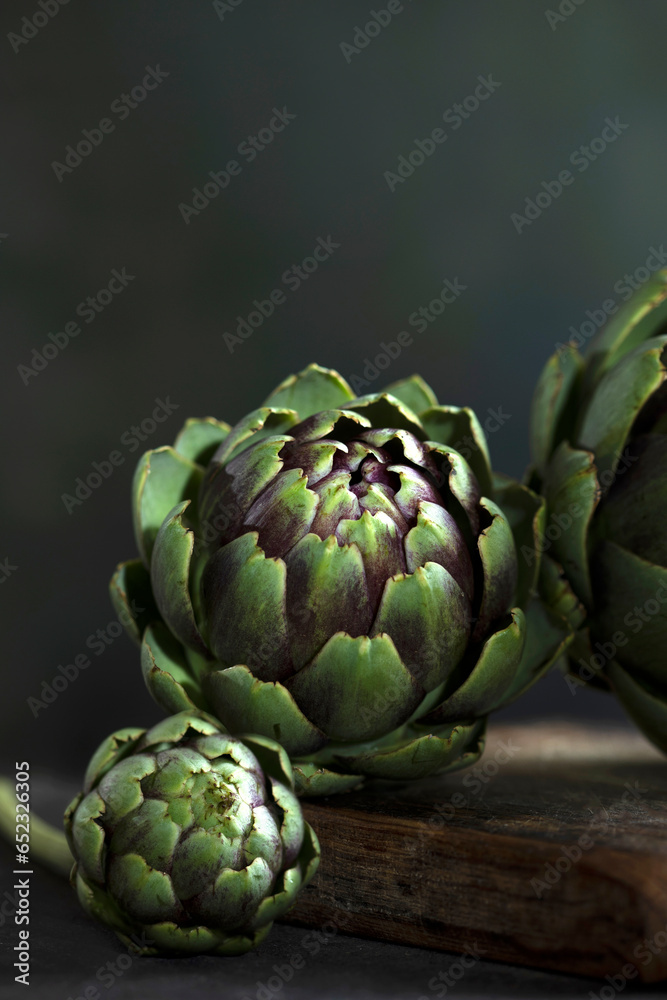 Obraz premium Green artichokes close-up.Dark background. Vertical photo.Copy space.