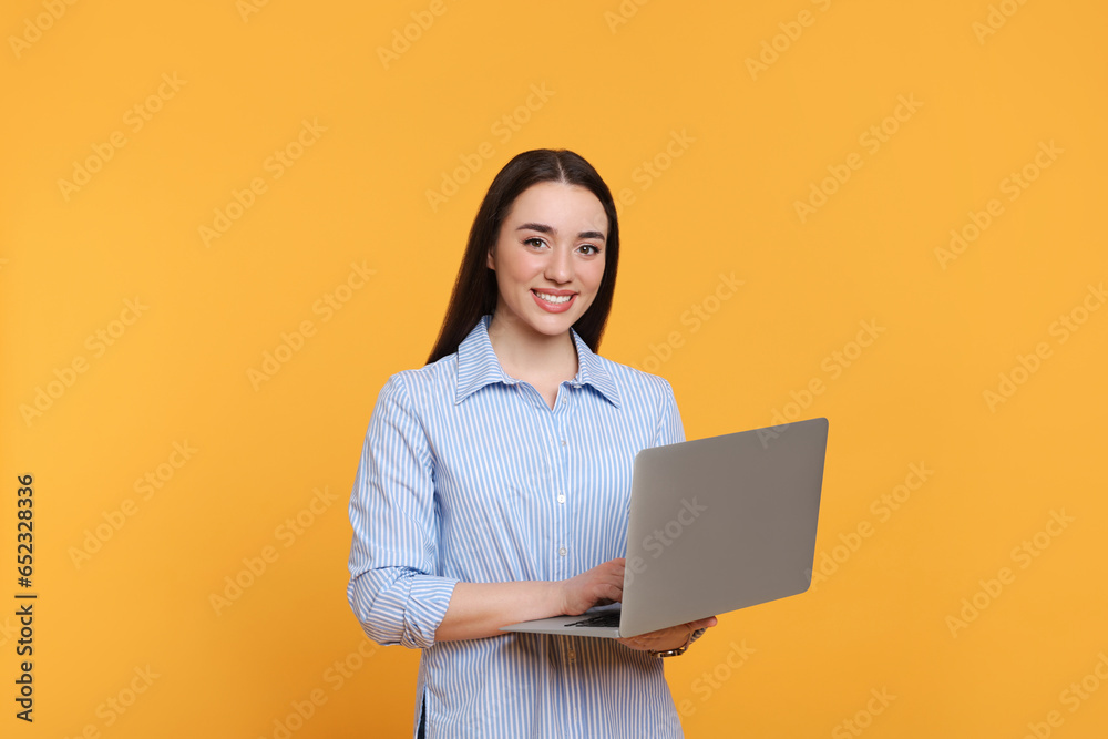 Smiling young woman with laptop on yellow background Smiling young woman with laptop on yellow background