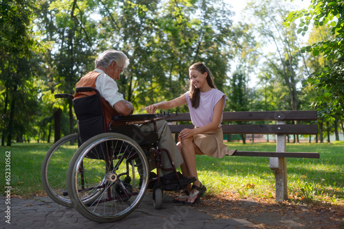 A young caregiver playing chess, talking and spending quality time with lonely senior client in the city park. Elderly healthcare and mental health. 