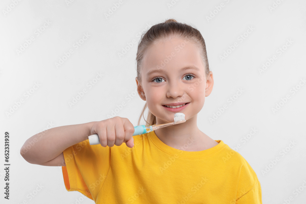 Happy girl brushing her teeth with electric toothbrush on white background Happy girl brushing her teeth with electric toothbrush on white background