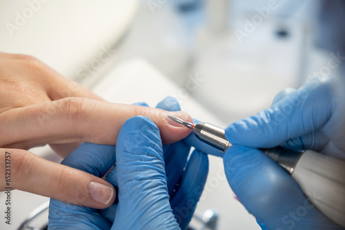 Nail care procedure in a beauty salon. Female hands and tools for manicure  process of performing manicure in beauty salon. Concept spa body care. Gloved hands of a skilled manicurist cutting cuticles