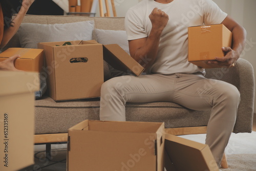 Beautiful young couple in love having fun unpacking things from cardboard boxes while moving in together in their new apartment