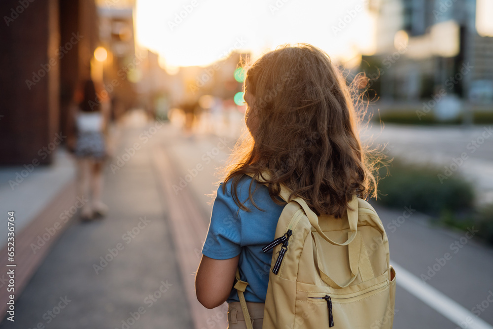 Rear view of a girl with a backpack goging to school in the morning. - obrazy, fototapety, plakaty 