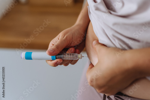 Close up of needle injecting insulin in abdomen. photo
