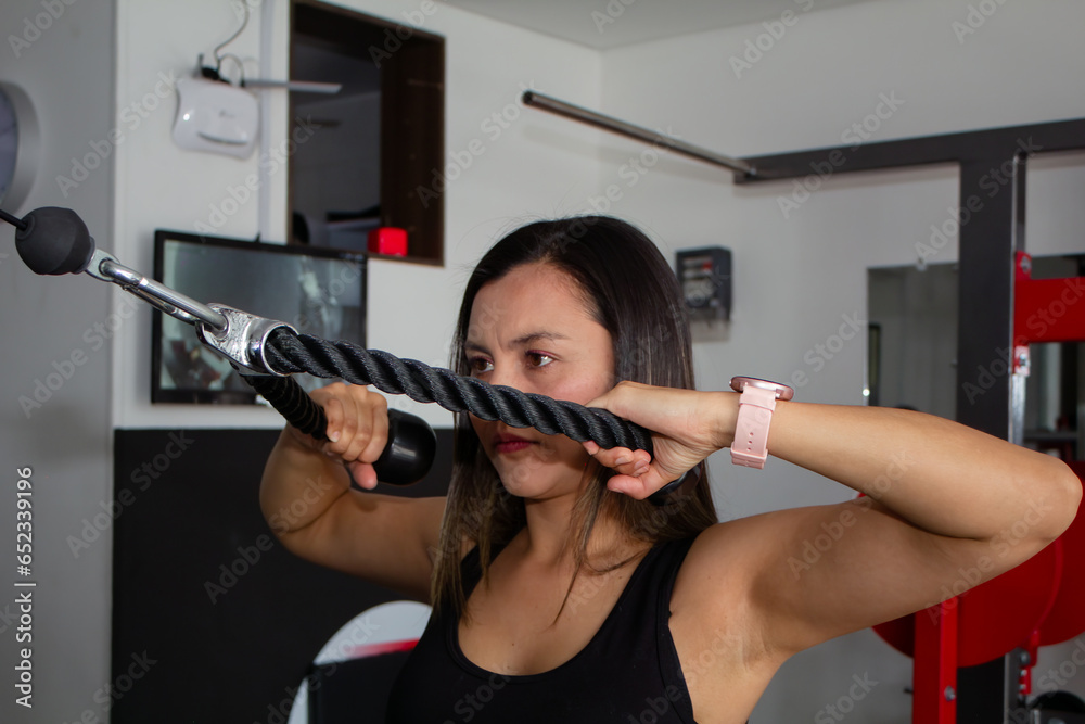 Sporty woman exercising on multi station at gym for arm and shoulders muscles. Fitness exercising in gym Sporty woman exercising on multi station at gym for arm and shoulders muscles. Fitness exercising in gym