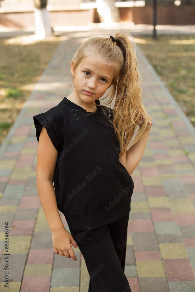 a large portrait of a blonde girl with big eyes and a ponytail in a black jacket
