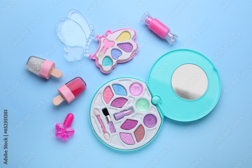 Eye shadow palette and other decorative cosmetics for kids on light blue background, flat lay - obrazy, fototapety, plakaty 