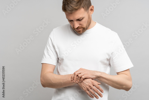 Man touching wrist of hand feeling pain on gray background. Tunnel syndrome, neuralgia, pinched nerve in arm after injury, consequences of computer work. Health problems, discomfort, symptom concept.