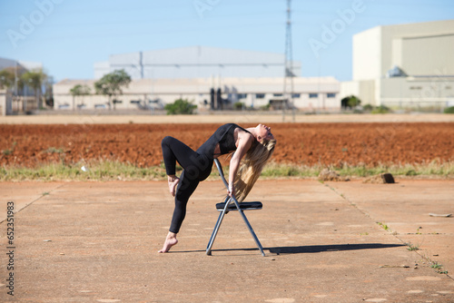 young, beautiful blonde woman dressed in sports clothes doing different aerobic exercises on a chair. Sport and health concept.