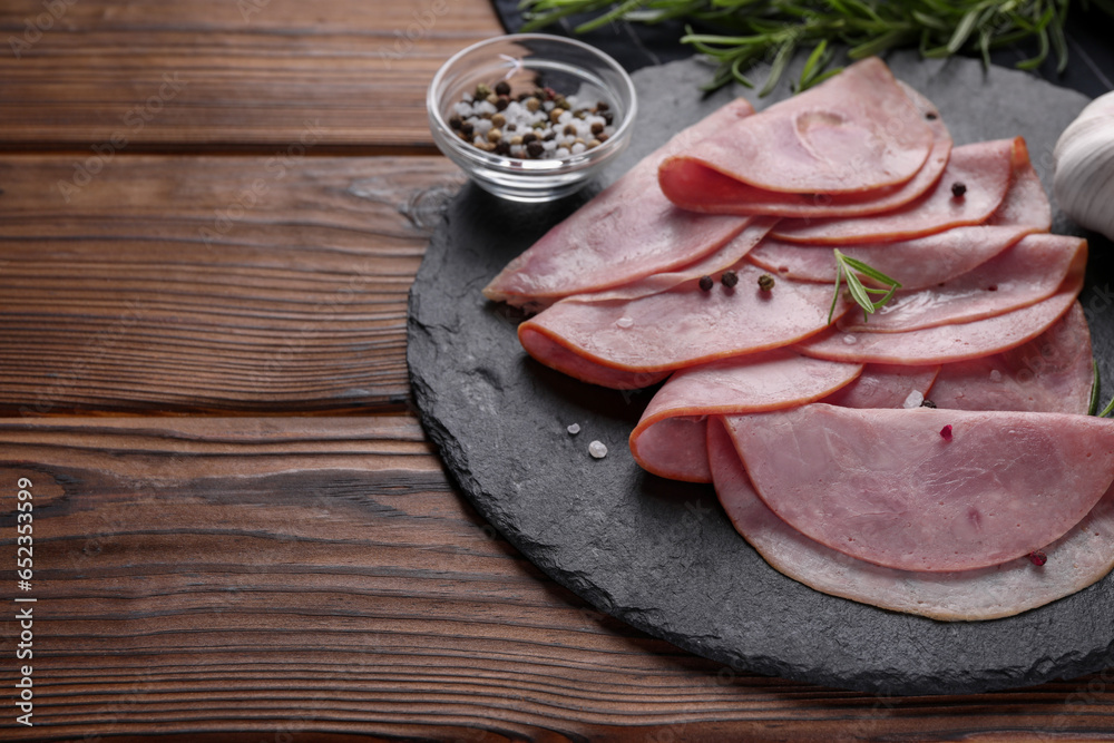 Tasty ham with rosemary, sea salt and peppercorns on wooden table. Space for text