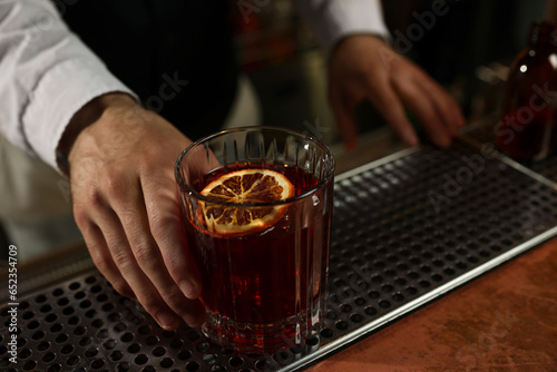 Bartender with fresh alcoholic cocktail at bar counter, closeup. Space for text