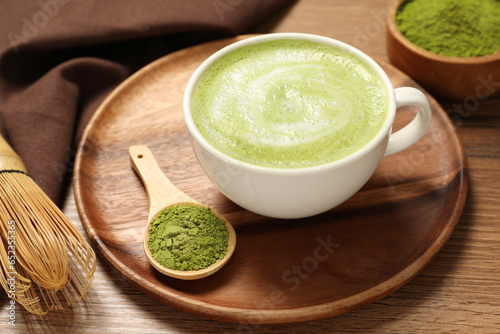 Cup of fresh matcha latte and powder on wooden table