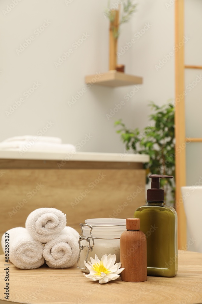 Different spa products and beautiful flower on wooden table in bathroom
