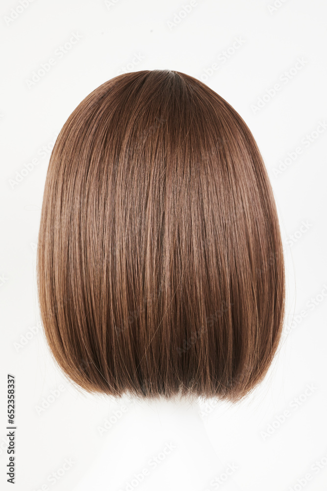 Natural looking dark brunet wig on white mannequin head. Middle length brown hair on the plastic wig holder isolated on white background, back view. Natural looking dark brunet wig on white mannequin head. Middle length brown hair on the plastic wig holder isolated on white background, back view.