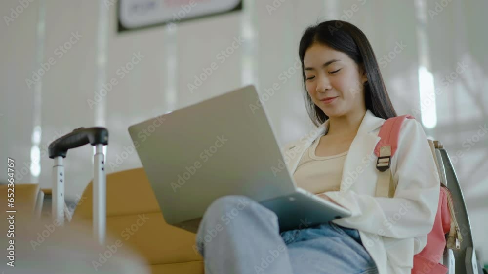 Young asian woman with laptop and mobile phone for work sits on chair waiting for flight in terminal hall area, she checks her phone and emails before boarding plane. Young asian woman with laptop and mobile phone for work sits on chair waiting for flight in terminal hall area, she checks her phone and emails before boarding plane.