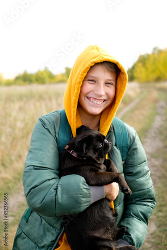 Teen boy with a dog walking in the park on a sunny yellow autumn. Friendship of boy and animal, animal owner. Portrait of boy with pet.