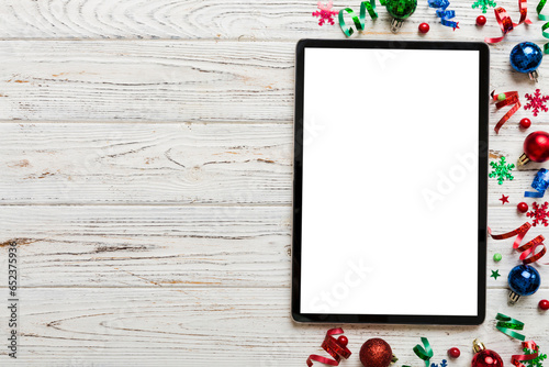 Christmas online shopping from home tablet pc with blank white display top view. Tablet with copy space on colored background with Christmas decorations balls,. Winter holidays sales background