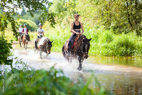 Horse ride, young girls riders, crossing a river, a stream on horseback, splashes from horse hooves, a picturesque place.