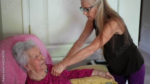 Closeup of elderly woman getting massage on her neck scalene muscles by home healthcare professional while sitting in her chair at home in her living room.