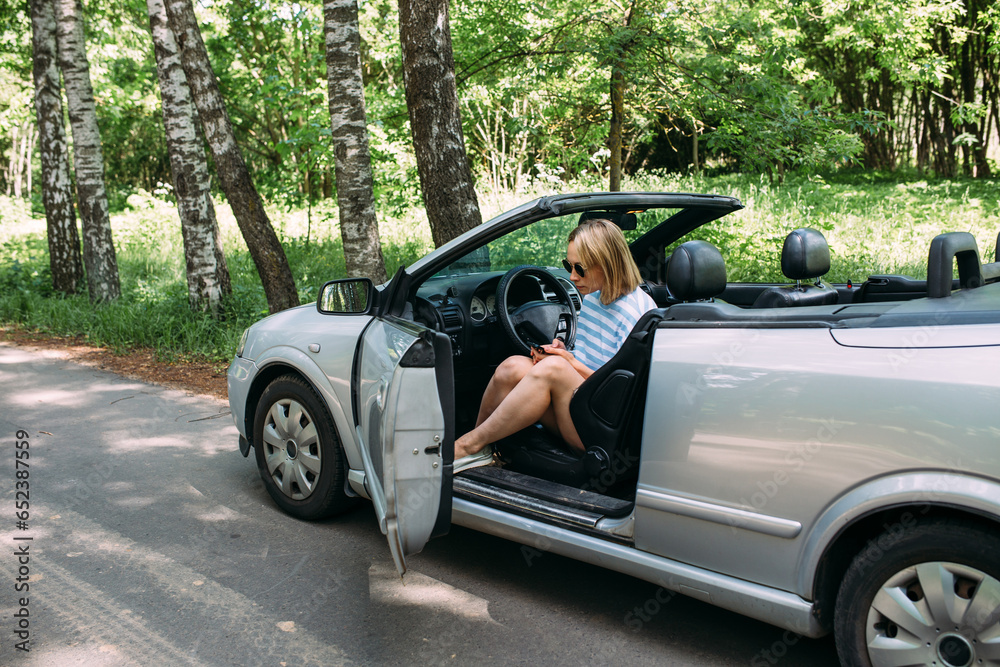 A woman is driving a convertible car. Summer road trip to nature A woman is driving a convertible car. Summer road trip to nature