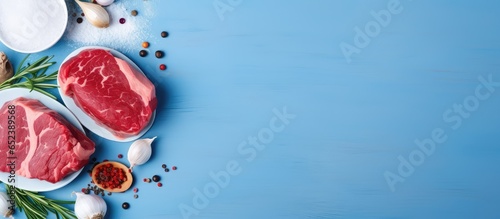 Serving of raw beef slices with onions and red peppers on a blue table isolated pastel background Copy space