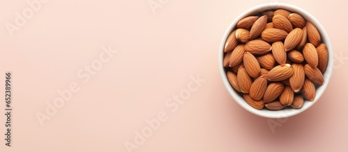 Almonds in a white bowl on a isolated pastel background Copy space with copy space have benefits for neutralizing free radicals preventing Alzheimers and repairing the body