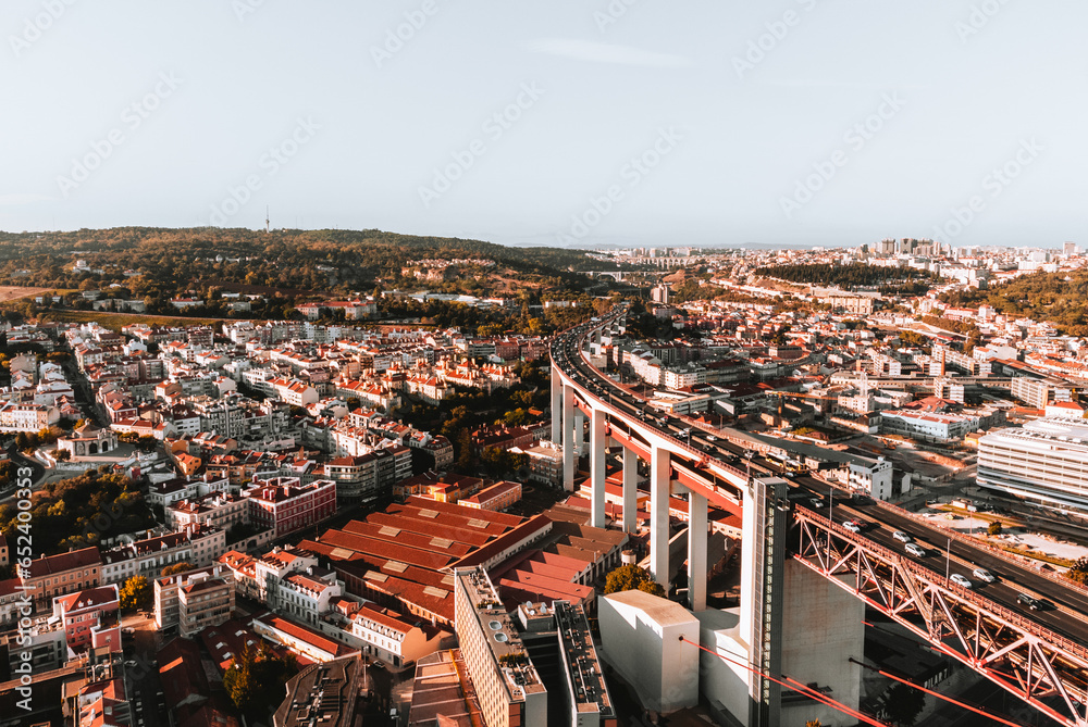 Aerial horizontal photo of streets and buildings of Lisbon on sunset. The Bridge of 25 april in Libson with historic city centre and rooftops from above on golden hour - taken by drone.