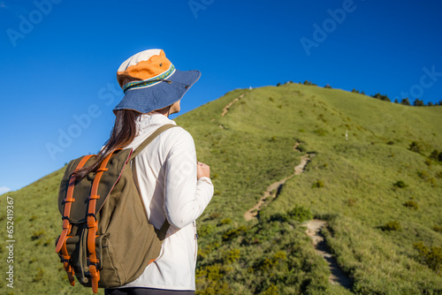 Girl on mountain peak with green grass looking at beautiful mountain valley