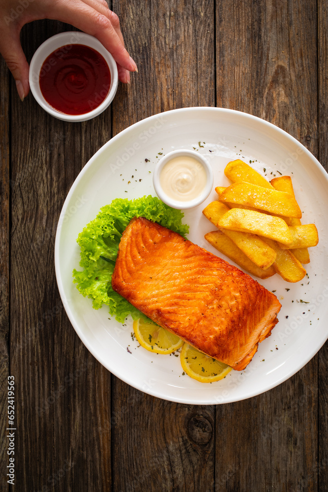 Seared salmon steak with French fries and fresh vegetables served on wooden table
Seared salmon steak with French fries and fresh vegetables served on wooden table