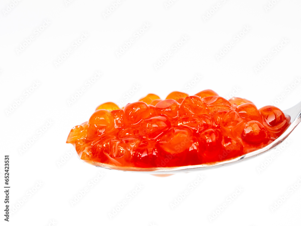 Spoon with red caviar on a white background. Red caviar close-up. Spoon with red caviar on a white background. Red caviar close-up.