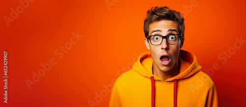 What just happened. Portrait of a shocked young man wears glasses on colour background.