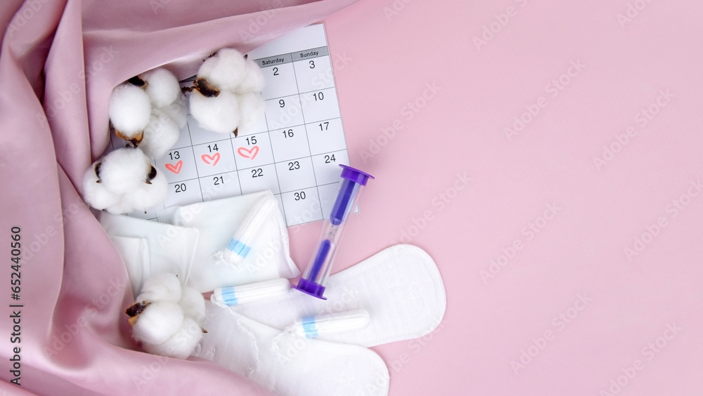 Women's menstrual pads, tampons, female menstruation calendar and alarm clock on a pink background. - obrazy, fototapety, plakaty 