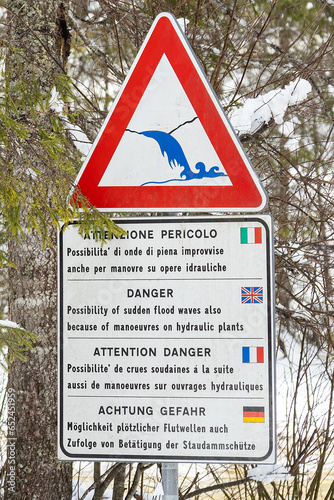 High water danger sign. Possibility of sudden flood waves after manoeuvres on hydraulic plants by Rienz river in a snowy winter day; Toblach (Dobbiaco), Bolzano, Italy; Dolomites photo