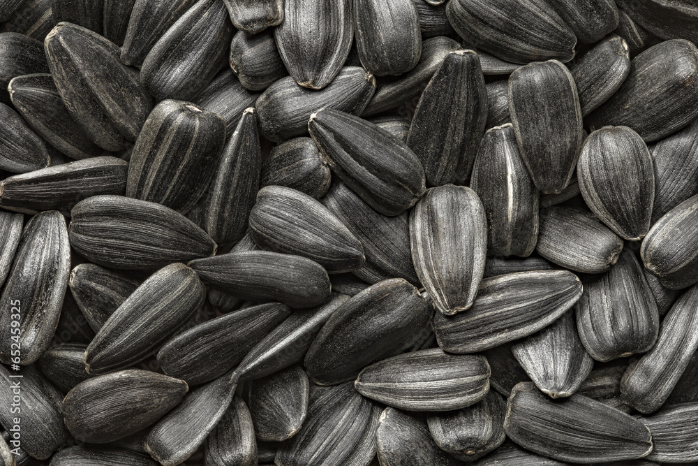 Sunflower seeds, black, unpeeled, in bulk, close-up, uniform texture background . - obrazy, fototapety, plakaty 