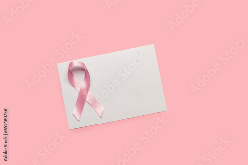 Un sobre en blanco con un lazo rosa sobre un fondo rosa pastel liso y aislado. Vista superior y de cerca. Copy space photo