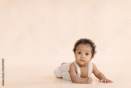 African cute baby looking at the camera on a beige background, in the style of minimalism