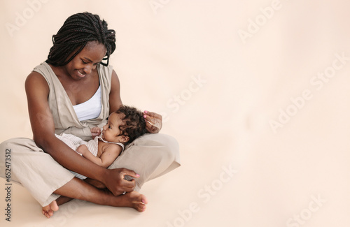 African-American mother with baby on beige background Minimalist portraits, space for text
