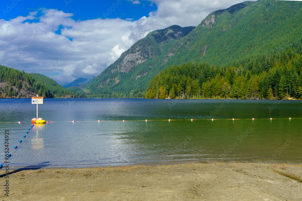Buntzen Lake, BC, viewed from beach on a cloudy summer day, with spectacular mountain backdrop.