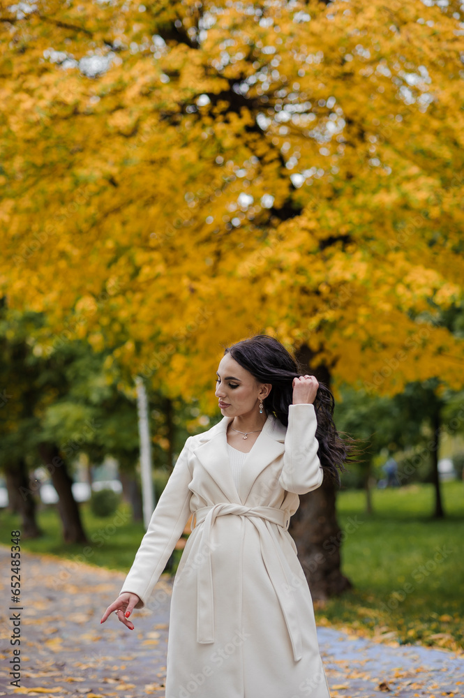 Girl in a white coat in an autumn park
