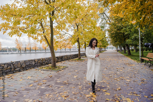 Girl in a white coat in an autumn park photo