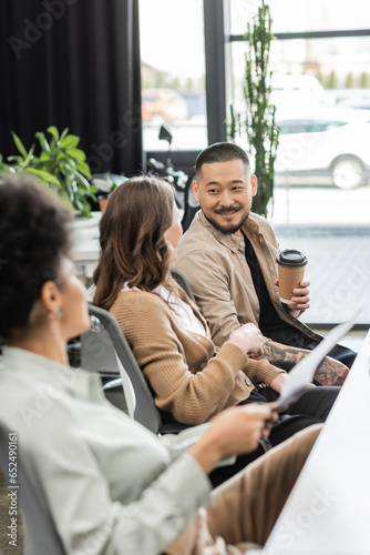 joyful asian businessman holding coffee to go and chatting with female colleague in modern coworking Free Download joyful asian businessman holding coffee to go and chatting with female colleague in modern coworking - GFXLoad