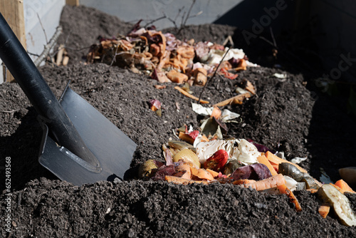Shovel and bokashi compost. Pre-fermented food waste to be added to the soil in the garden bed. Bokashi compost added to the ground to decompose further into nutrient rich soil for organic gardening.