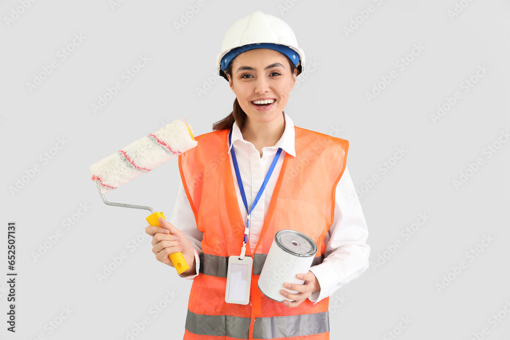 Female decorator with paint and roller on light background Female decorator with paint and roller on light background